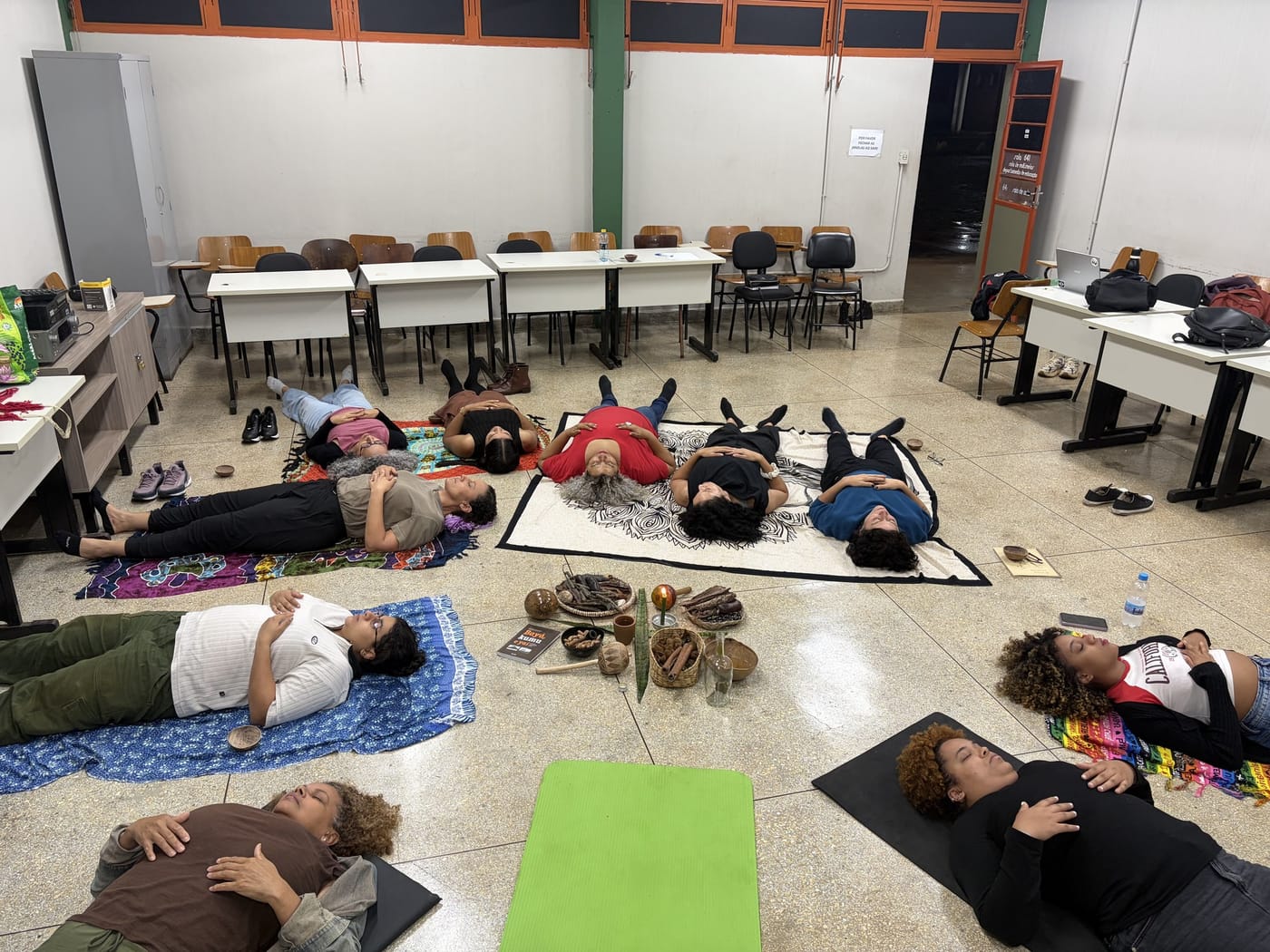 Grupo deitado em relaxamento durante uma prática em sala
