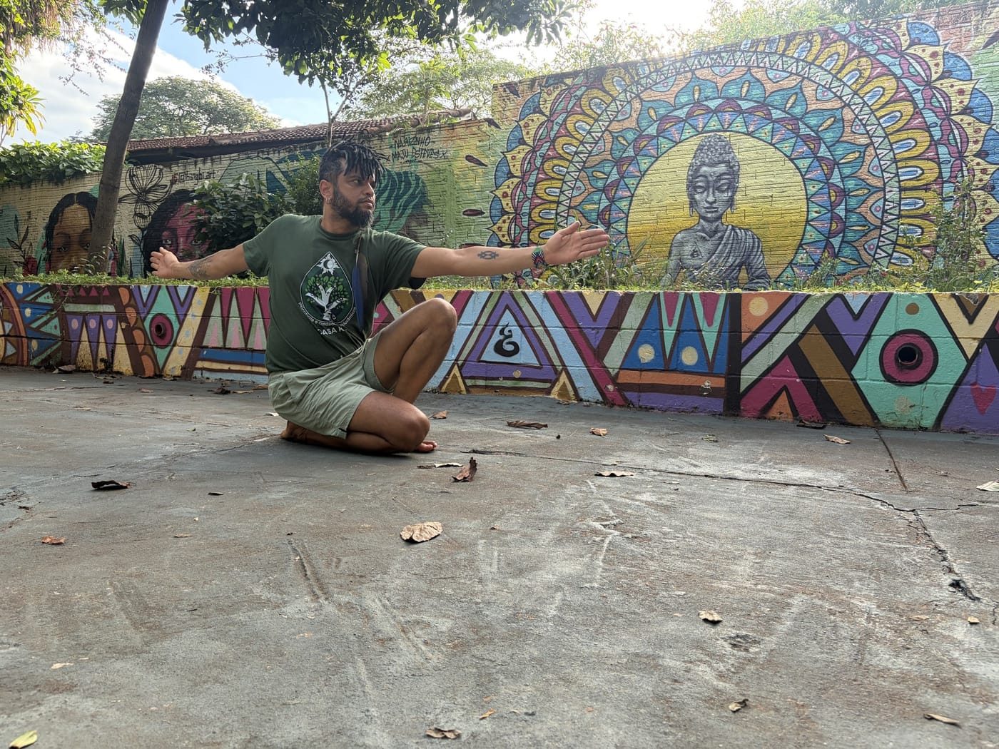 Keâ Costa orientando a prática diante de um mural colorido